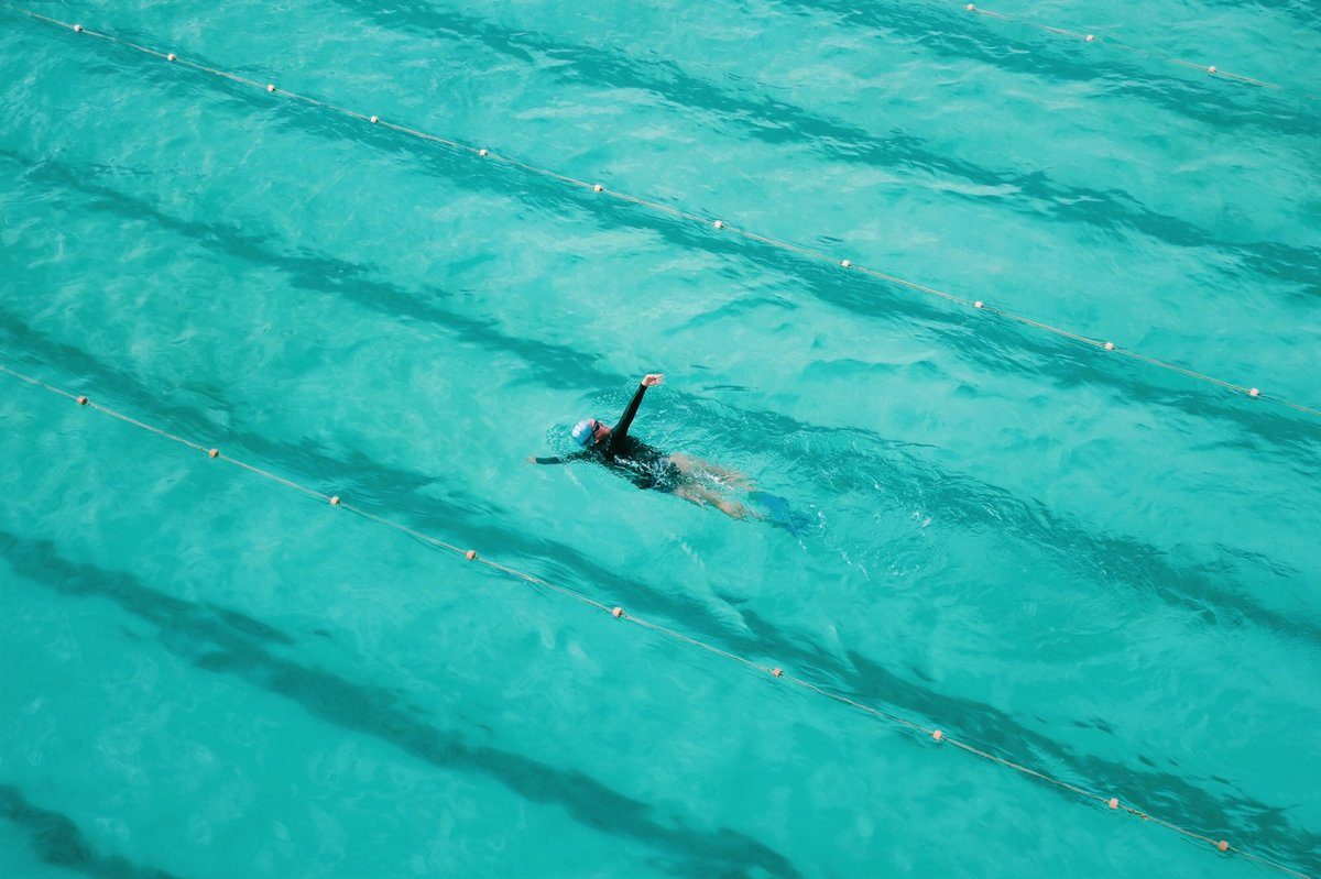 Nageur vu d'en haut dans un bassin à l'eau turquoise