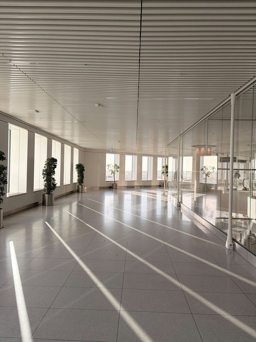 Salle vide et lumineuse avec des lignes tracées au sol et de grandes baies vitrées